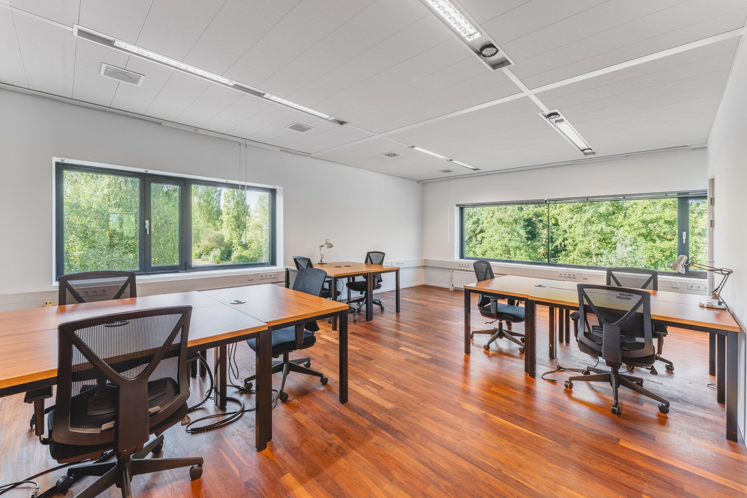 Lichte en moderne kantoorruimte aan de Prof. W.H. Keesomlaan met meerdere bureaus, bureaustoelen en uitzicht op groen.